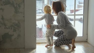 Küçük bebek ve annesi pencereden dışarı bakarak