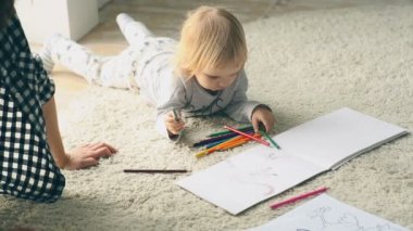 Kız bebek resim kalemleri ile çizer.