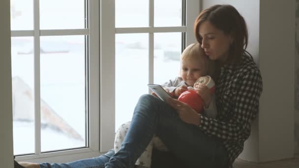 Madre usando un teléfono inteligente con un bebé pequeño en sus rodillas — Vídeos de Stock