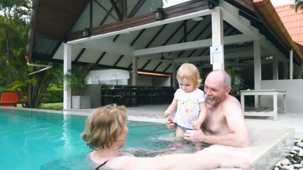 Grandparents playing with child in swimming pool — Stock Video