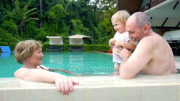 Grandparents playing with baby girl in swimming pool — Stock Video