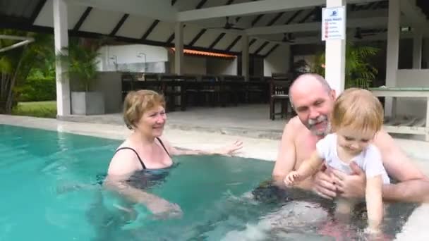 Abuelos jugando con su nieta en la piscina — Vídeo de stock