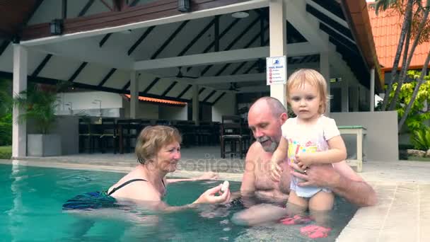 Abuelos se divierten con su nieta en la piscina — Vídeo de stock