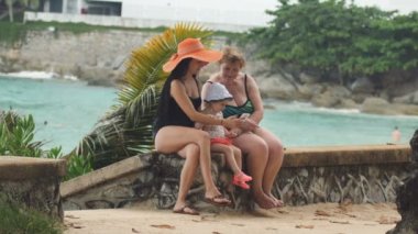 Küçük bebek sahil şeridi üzerinde smartphone kullanarak kadınlarla