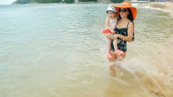 Woman walking along coastline with baby girl — Stock Video