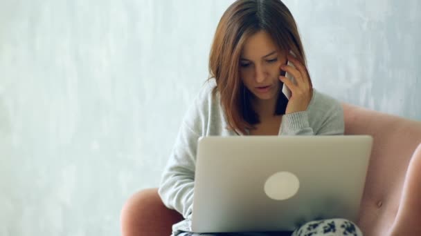 ノート パソコンで自宅で仕事と携帯電話で話している女性 — ストック動画