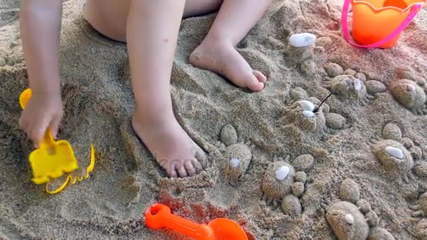 Petite fille joue avec des jouets dans le sable — Video