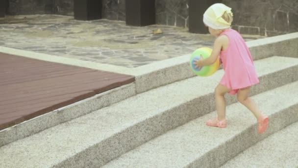 Baby flicka klättring på stege med boll — Stockvideo
