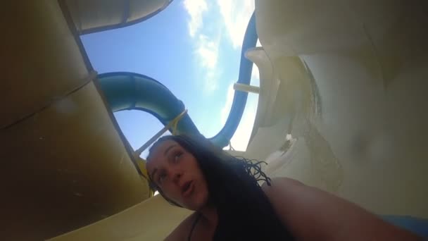 Счастливая девушка едет на горке аквапарка — стоковое видео