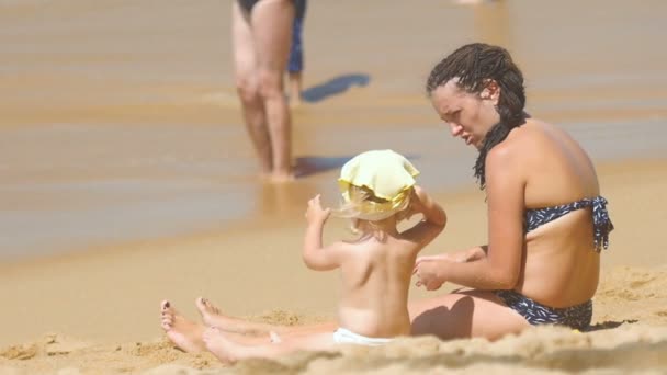 Fürdőruha ül a homokos strand a kislányom, és beszél a nő