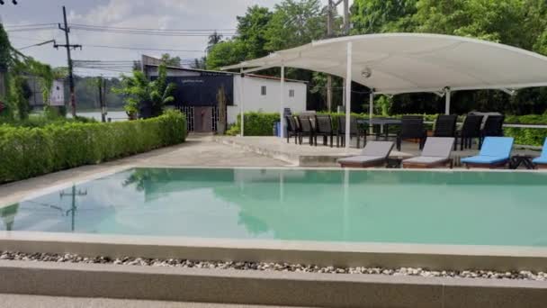 Panoramic view of swimming pool in resort hotel. Woman sunbathes near recliners. — Stock Video