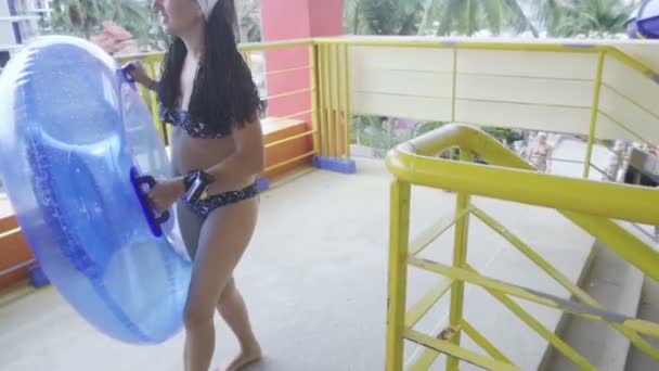 Chica con anillo de goma va a montar en tobogán parque acuático — Vídeo de stock