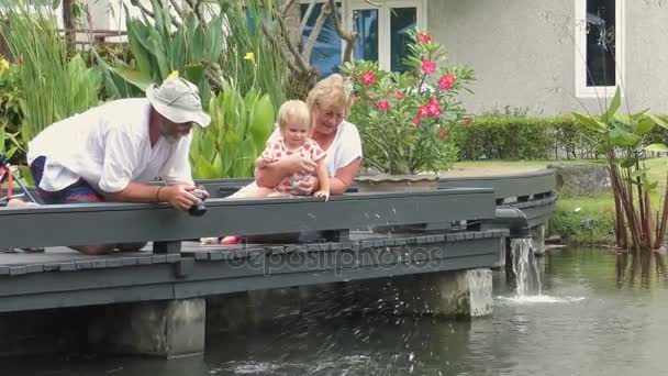 Abuelos con niños alimentando peces en el estanque — Vídeos de Stock