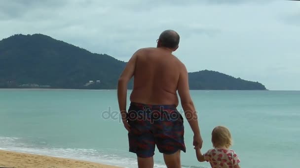 Abuelo sosteniendo a las niñas de la mano y camina por la playa — Vídeos de Stock