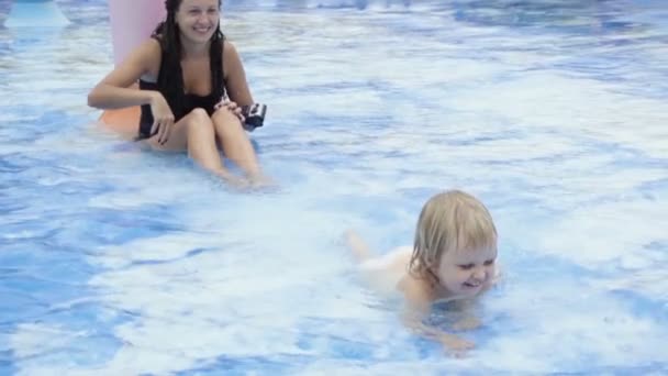 Niño arrastrándose en la piscina y la madre salpica el agua — Vídeo de stock