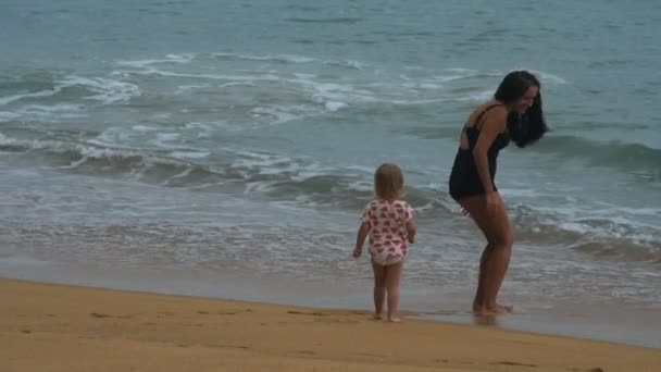 Madre e hija están corriendo en la playa de las olas del océano — Vídeos de Stock