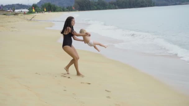 Mère tourne sa petite fille sur les bras et la plage de sable — Video