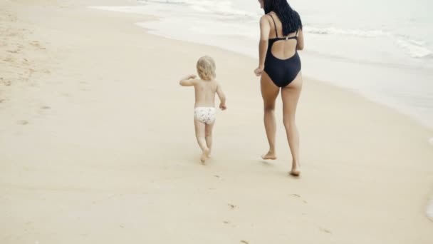 Мати і дочка біжать на пляжі — стокове відео