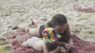 Küçük kızı kumsalda smartphone kullanarak ile anne çalış