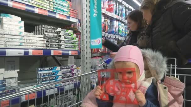 Pequena menina chata está esperando enquanto os pais estão comprando — Vídeo de Stock