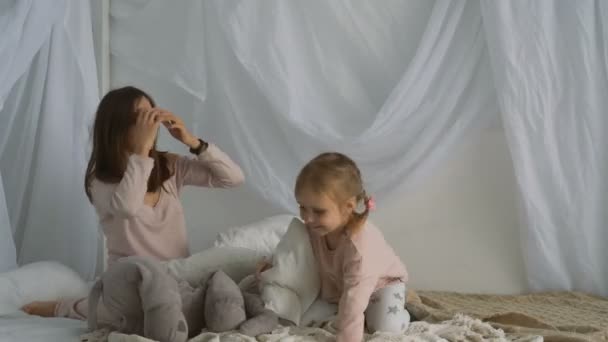 Beautiful woman and little girl play with pillows — Stock Video