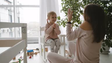 Sallanan içinde oturan küçük kız ve annesi ile oynamak