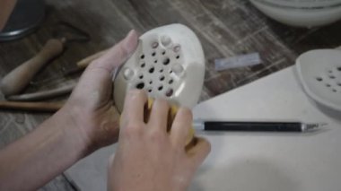 Islak süngerle kilden ürün silen kadın.