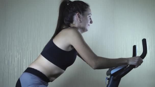 Entrenamiento de mujer en bicicleta estática en casa — Vídeos de Stock