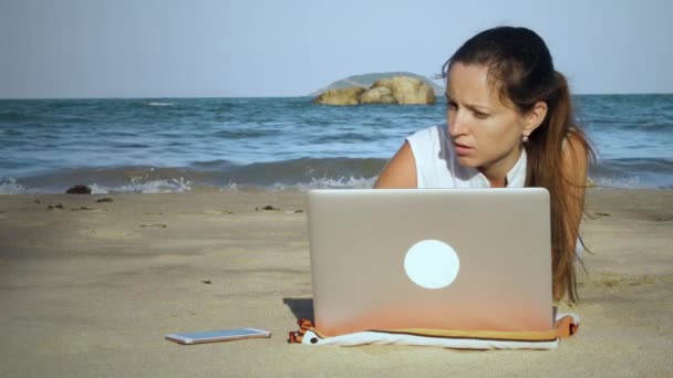 Chica freelancer usando el ordenador portátil en la playa — Vídeos de Stock