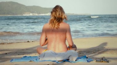 Young man in yoga pose on the beach