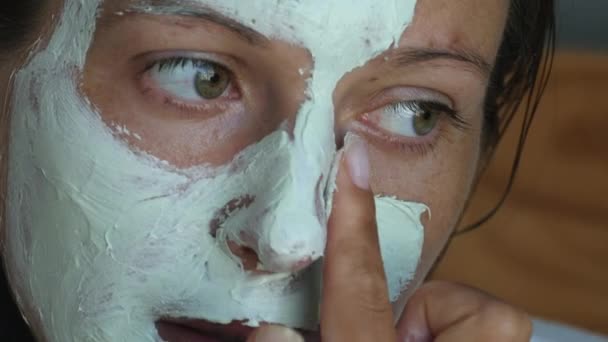 Vrouw die een zuiverend kleimasker op het gezicht aanbrengt — Stockvideo