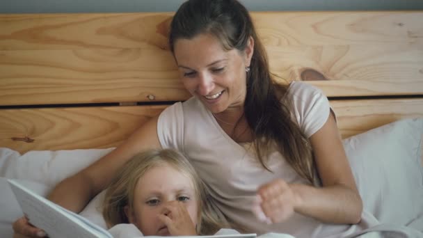 Mutter und Tochter lesen im Bett — Stockvideo