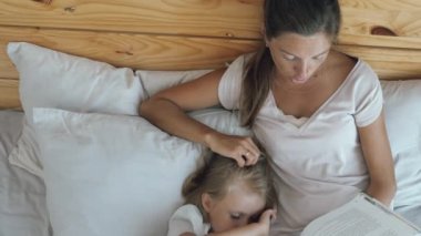 Mother with daughter reading in bed