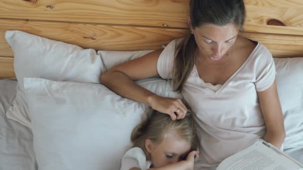 Мать с дочерью читают в постели — стоковое видео