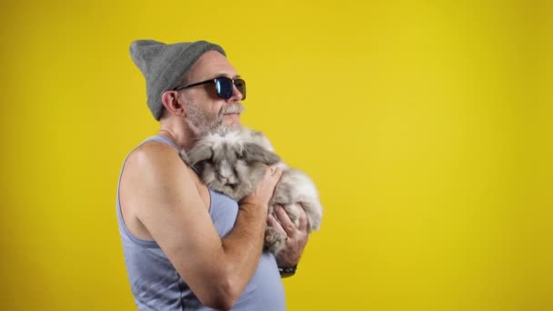 Old hipster man holding a cute bunny on hands. — ストック動画