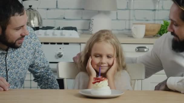 Chica soplando vela en la torta haciendo deseo — Vídeo de stock