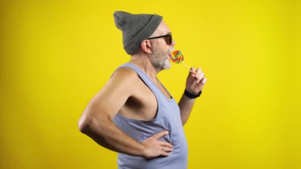 Trendy bearded senior man licking lollipop — Stockvideo