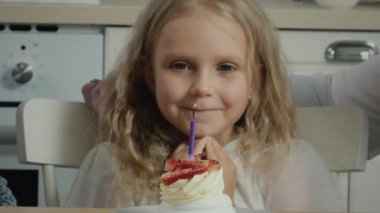 Birthday girl blowing candle on cake making wish