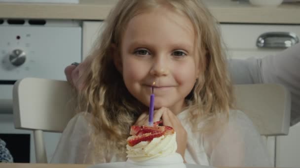 Именинница задувает свечу на торте загадывая желание — стоковое видео