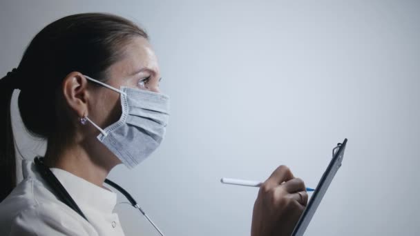 Ärztin in medizinischer Maske macht Notizen — Stockvideo