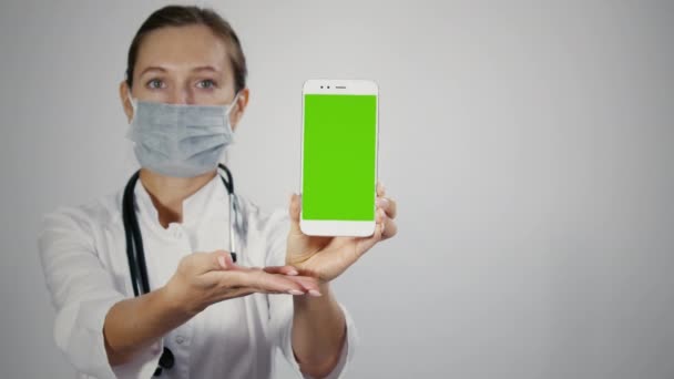 Profissional médico feminino exibindo smartphone móvel com greenscreen . — Vídeo de Stock