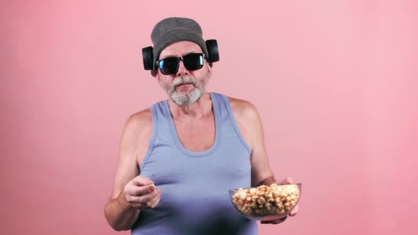 Gammal trendig man i solglasögon äter popcorn. — Stockvideo