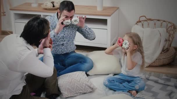 Papás y niña divirtiéndose con rosquillas — Vídeo de stock