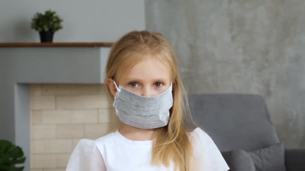 Девушка в медицинской маске и смотрит в камеру — стоковое видео
