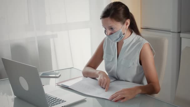 Podnikatelka v lékařské masce obličeje sedí proti notebooku — Stock video