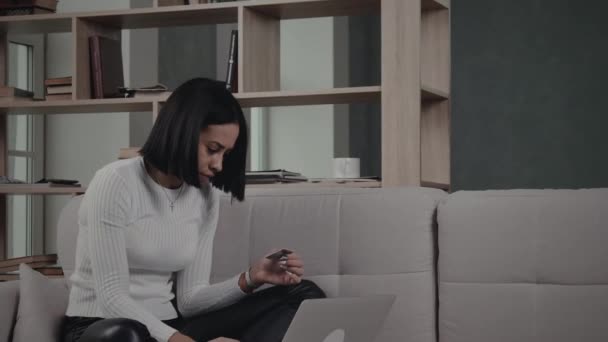 Mulher negra fazendo transação on-line no sofá — Vídeo de Stock