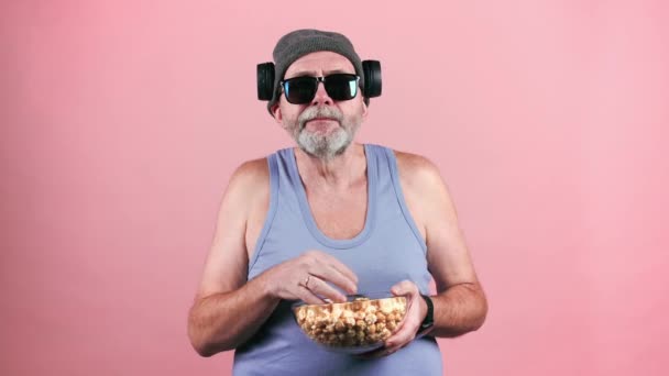 Зрілий модний чоловік в сонцезахисних окулярах їсть попкорн . — стокове відео