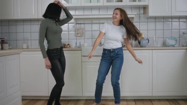 Пара женщин танцуют на кухне под музыку — стоковое видео