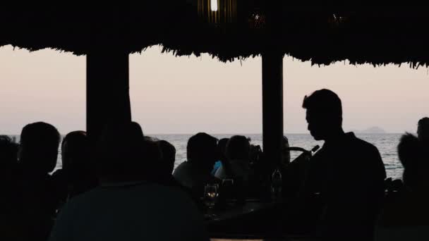 Silueta de la gente en el café de la playa al atardecer — Vídeos de Stock