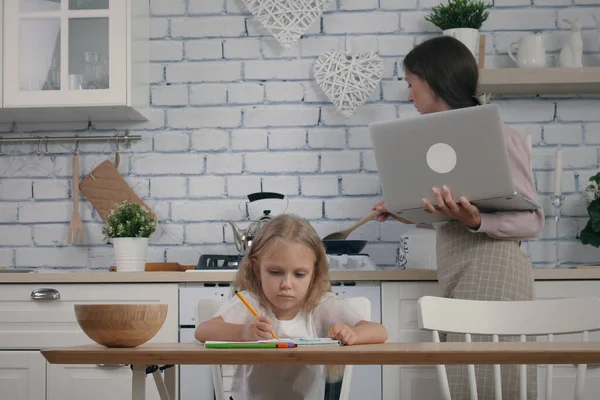 어머니와 살난딸은 부엌에 있었고 경우에는 격리되어 있었다 요리중에 앞치마를 노트북으로 로열티 프리 스톡 사진